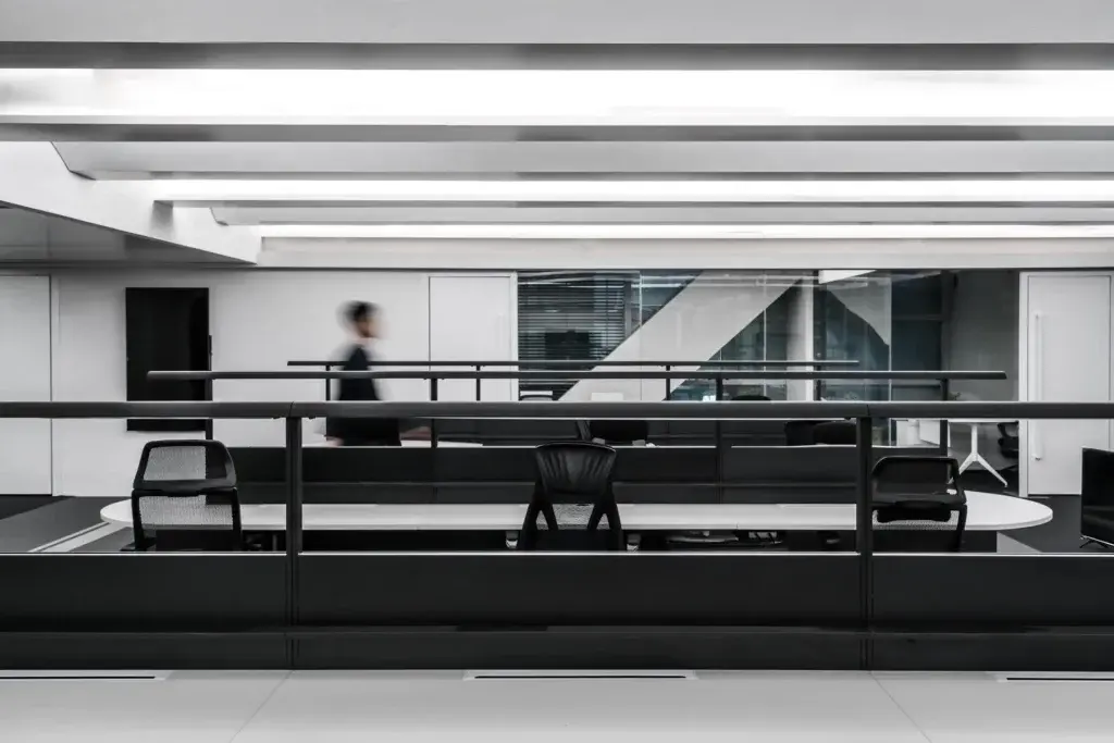 Person walking past a modern, minimalist office interior design in Hong Kong with a glass partition